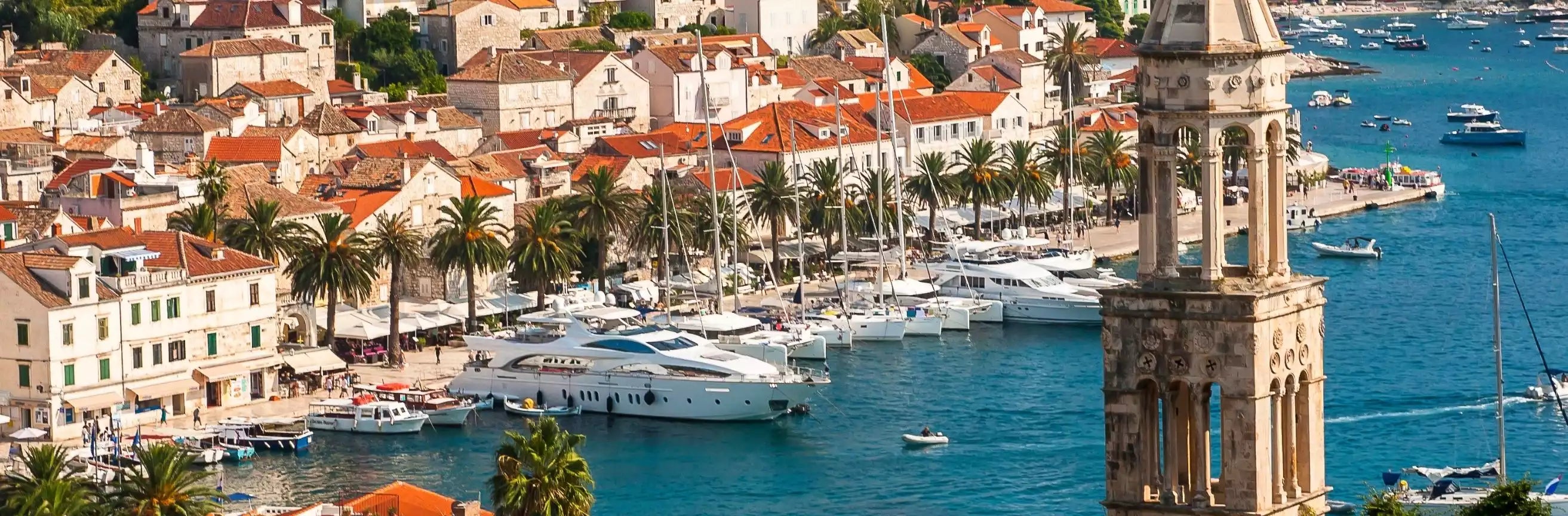 Harbor scene with boats, buildings, and a tall tower in a coastal town.
