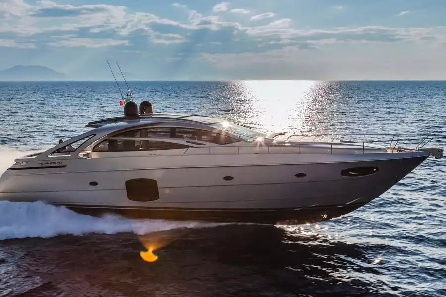 A luxury motor yacht with a white hull and dark glass superstructure sailing on open blue water under a bright sunlit sky.