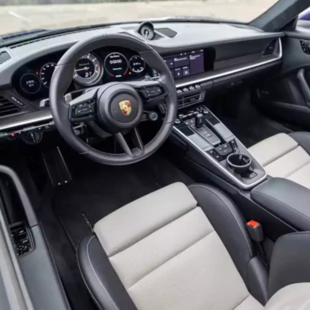 Car interior with steering wheel and dashboard of a Porsche vehicle.