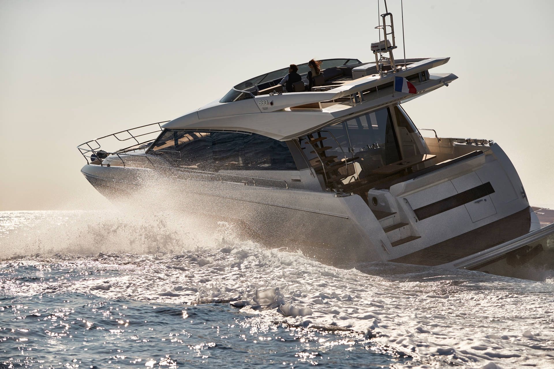 White yacht speeding on water with a clear sky background