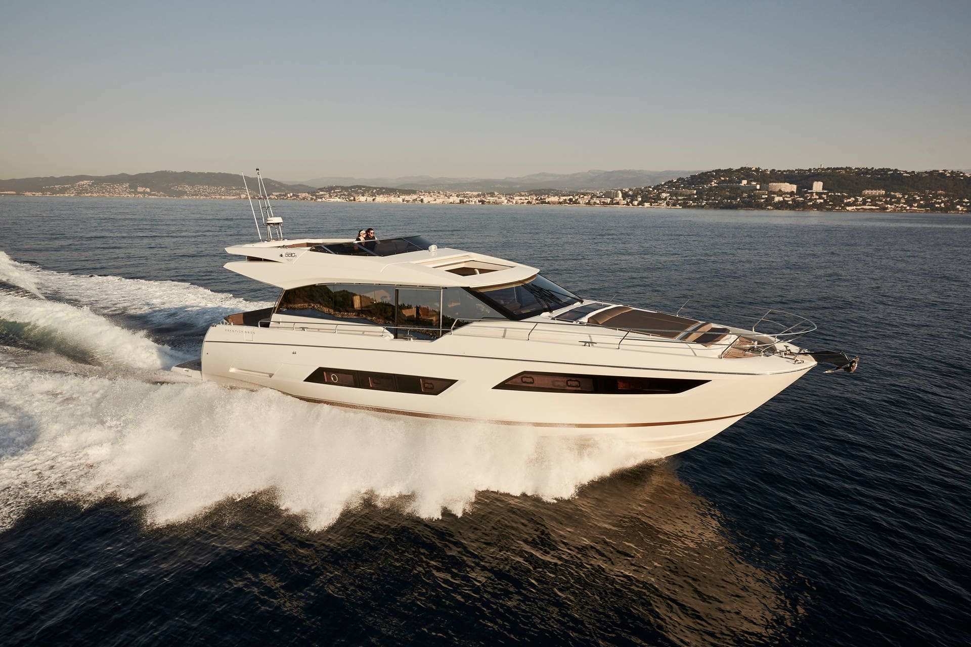 White yacht speeding on water with a cityscape in the background