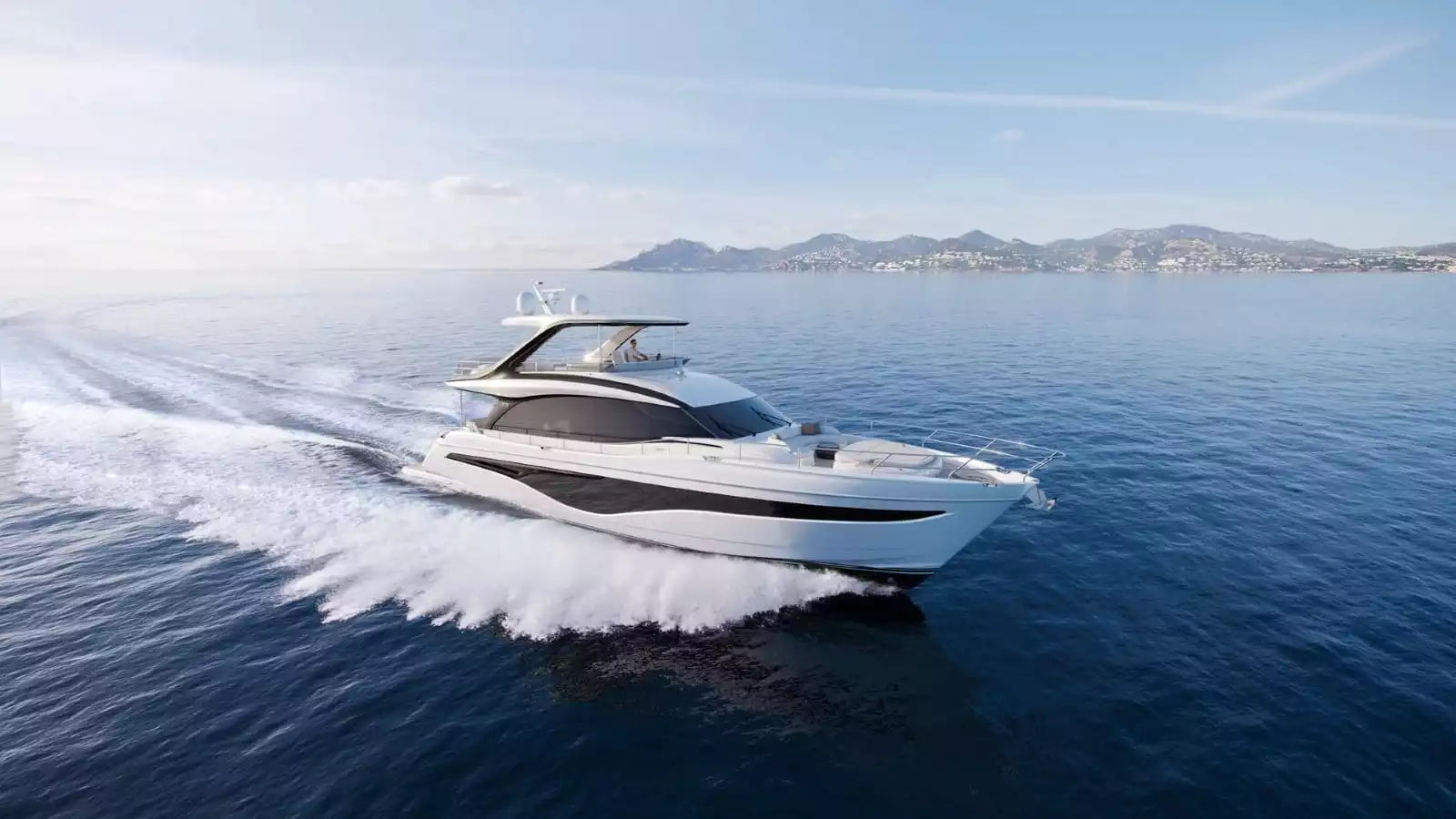A modern white motor yacht with black trim speeds across deep blue water, leaving a white wake, with distant mountains under a pale blue sky.
