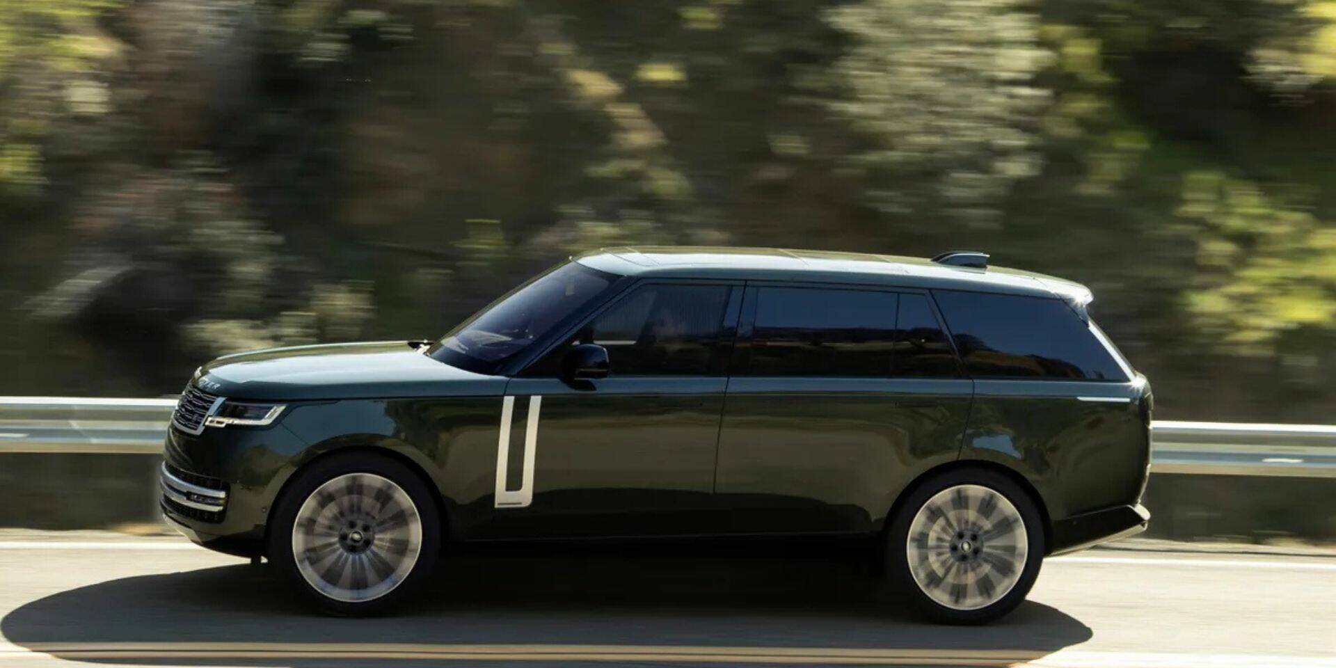 Black SUV driving on a road with blurred trees in the background