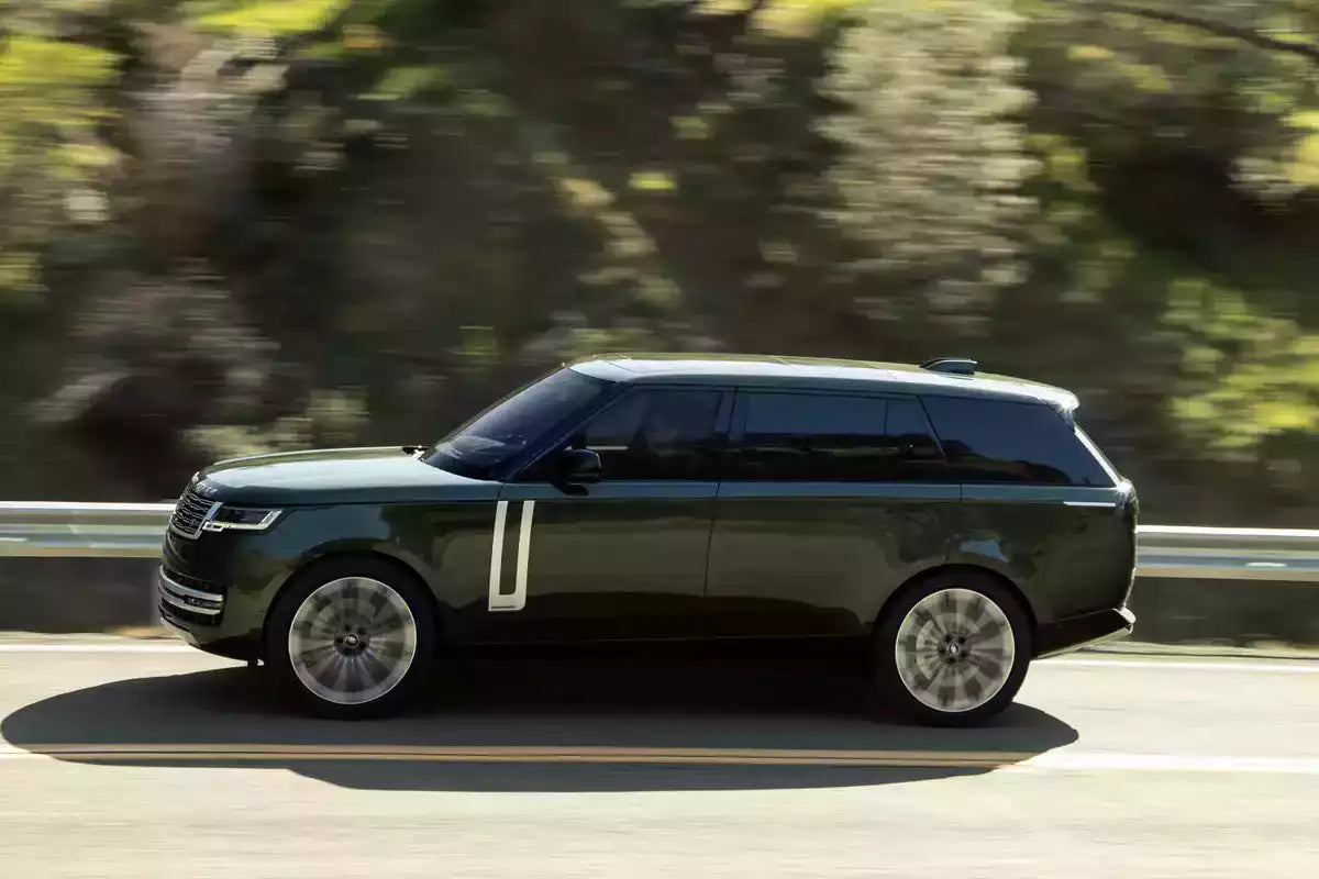 Green SUV driving on a road with blurred trees in the background