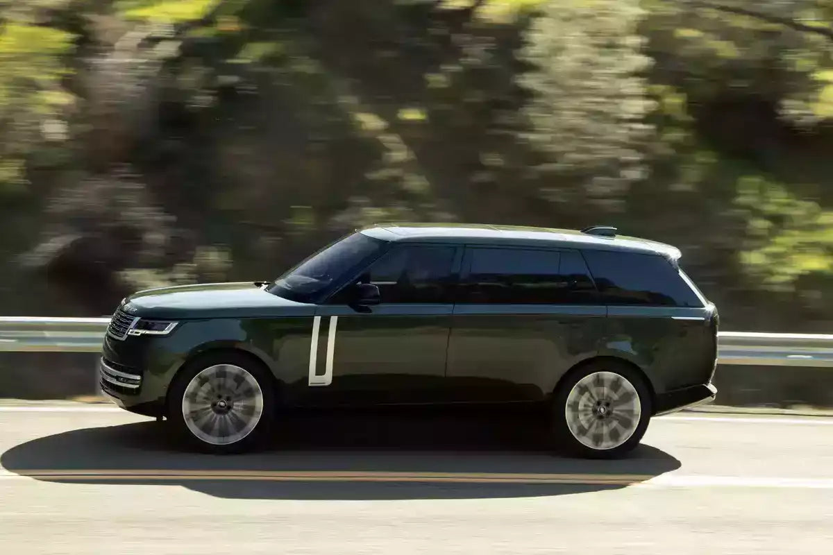 Green SUV driving on a road with blurred trees in the background