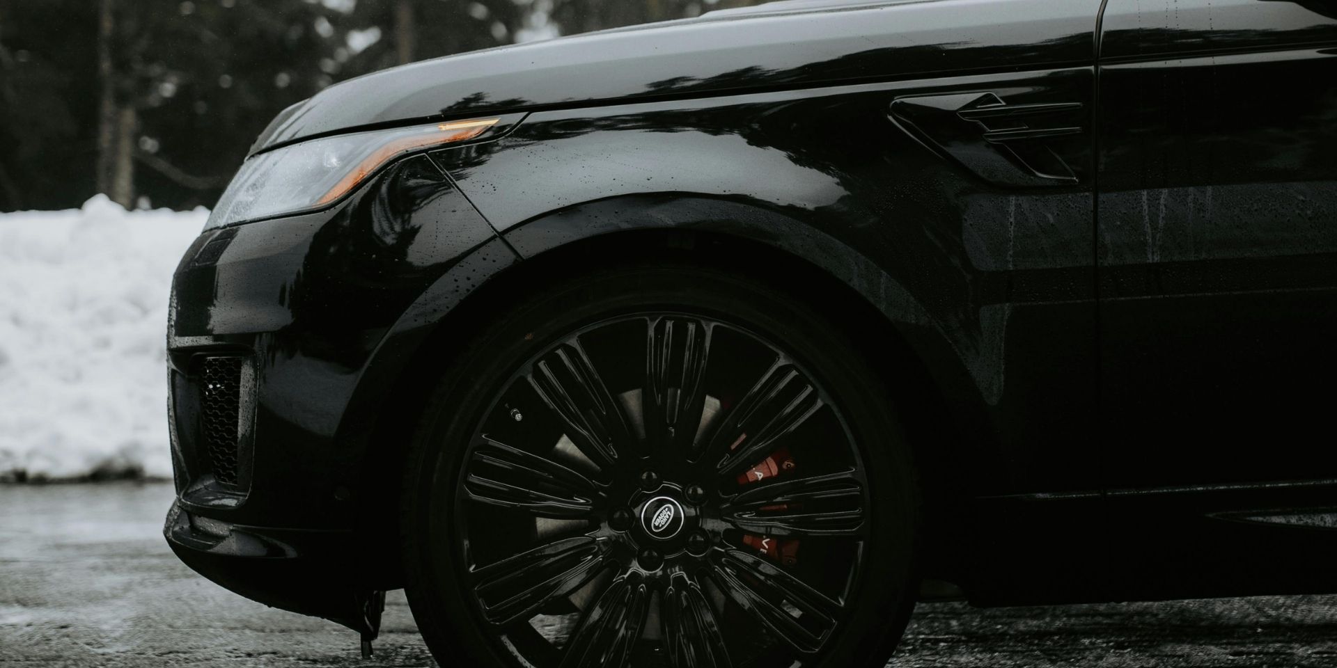 Close-up of a black luxury SUV with snow in the background