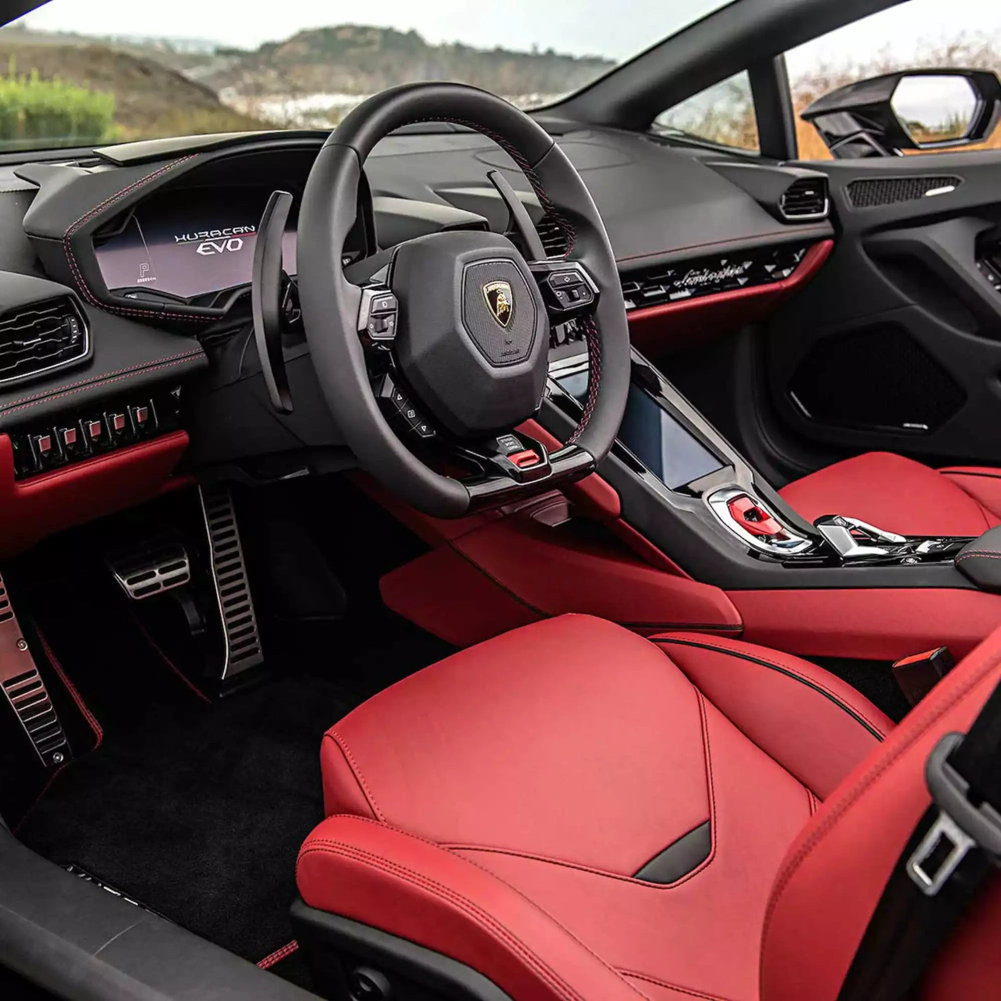 Luxury car interior with red seats and steering wheel, featuring a prominent logo.