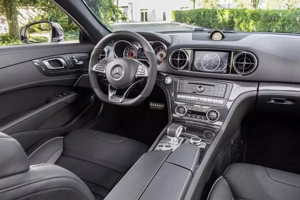 A luxury car interior featuring a black leather steering wheel with a Mercedes-Benz logo, a digital instrument cluster, a touchscreen infotainment system, and a center console with a gear shifter.