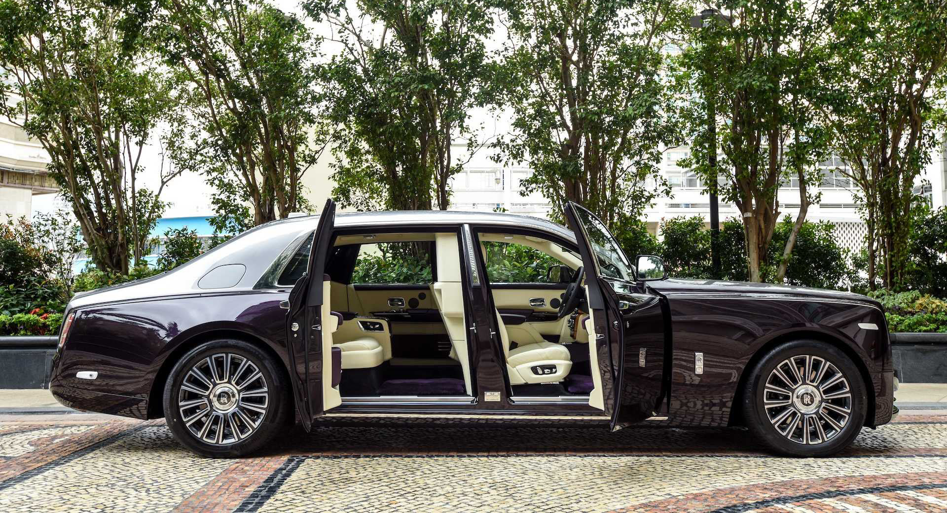 Luxury car with open doors on a tree-lined street