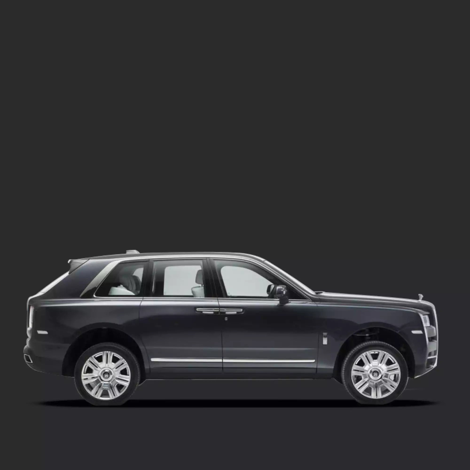 A side profile view of a black Rolls-Royce Cullion SUV with chrome accents and silver multi-spoke wheels, set against a solid dark gray background.