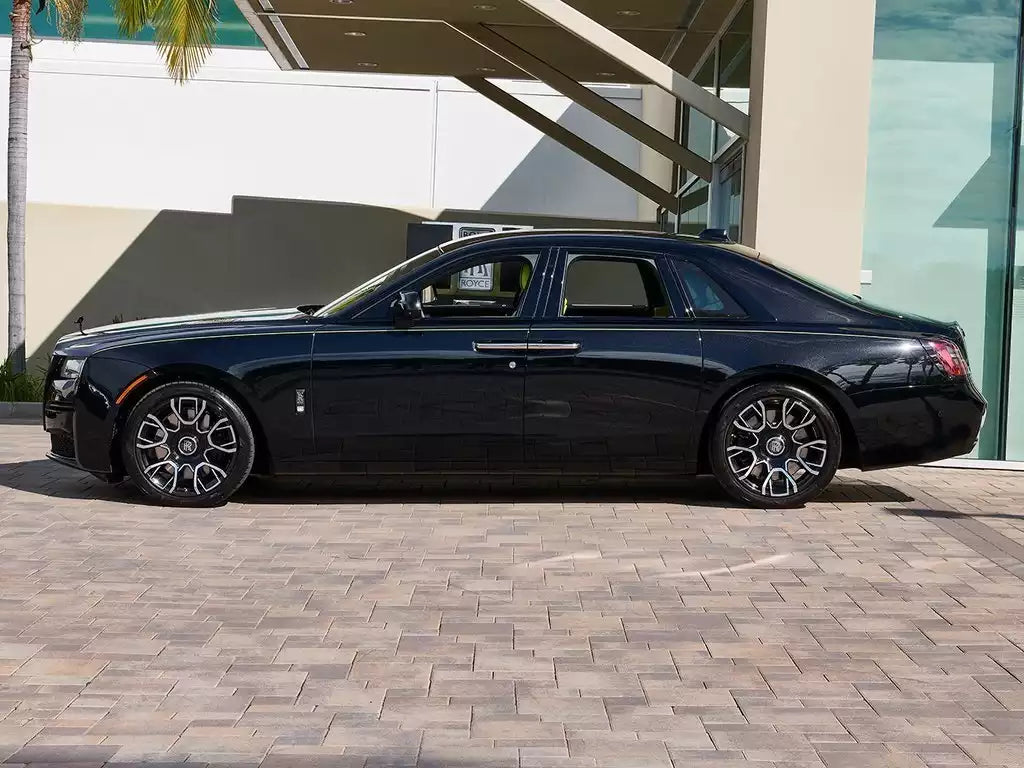 Black luxury car parked on a brick pavement with a building in the background