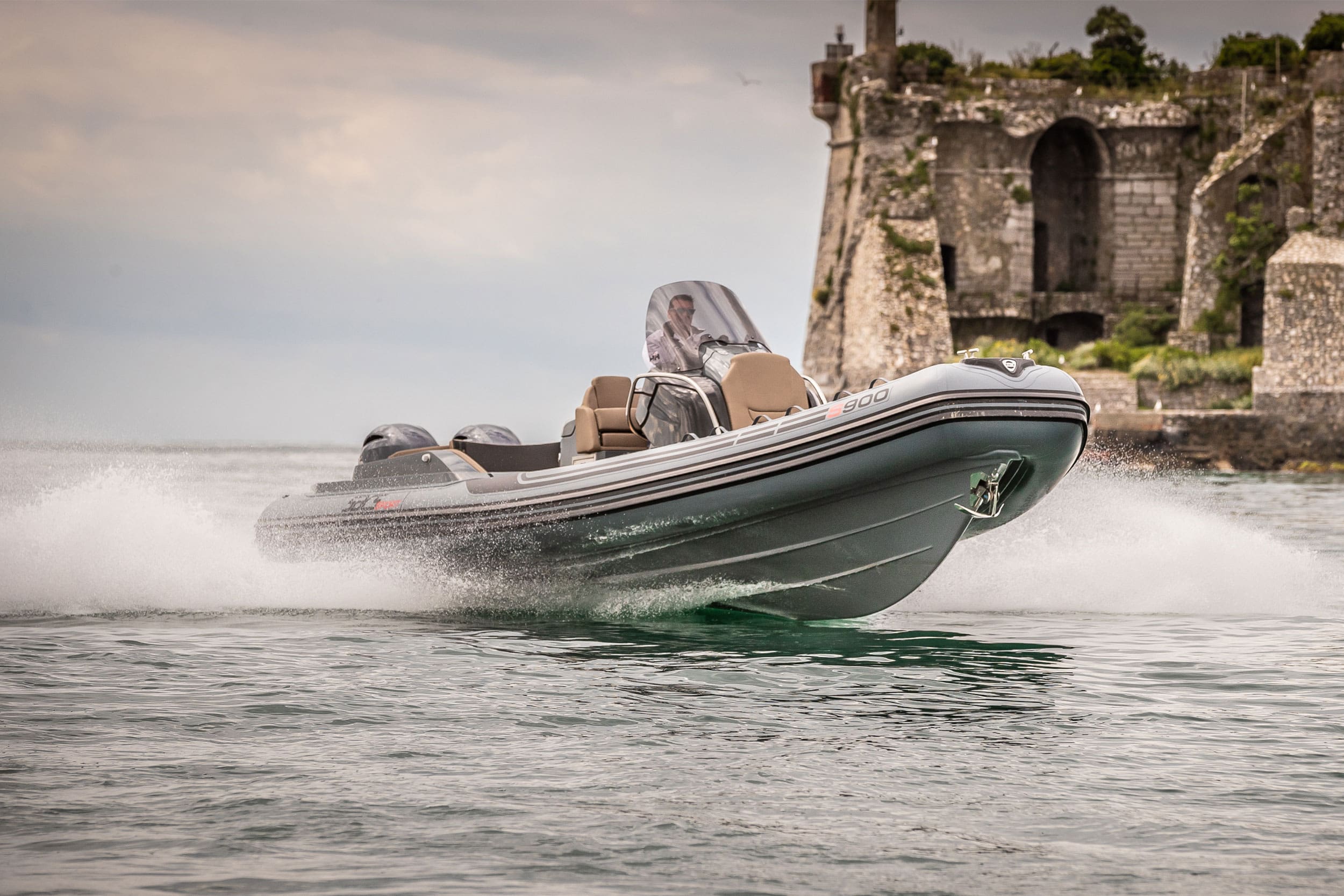 Rigid inflatable boat speeding on water with historical architecture in the background