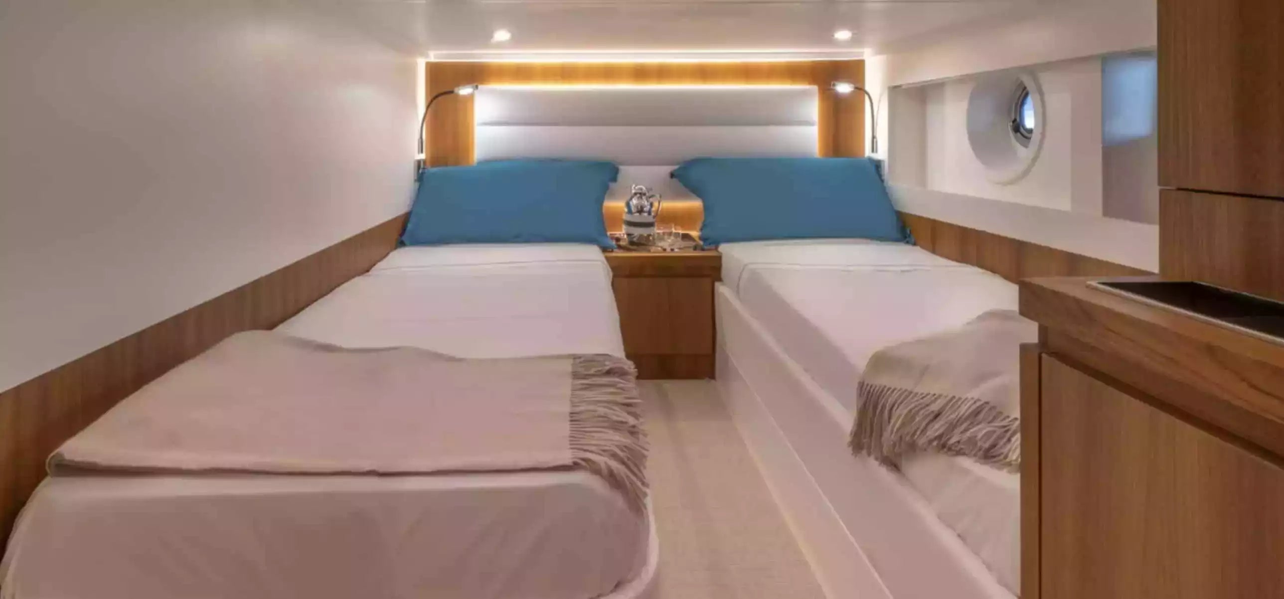 Nautical cabin with two beds, wooden paneling, and a small table.