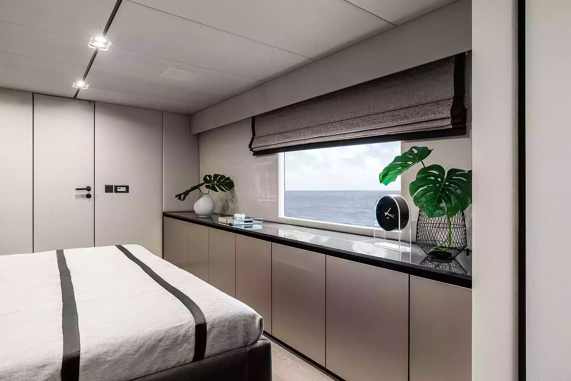 Modern bedroom with bed, window view of ocean, and decorative elements.