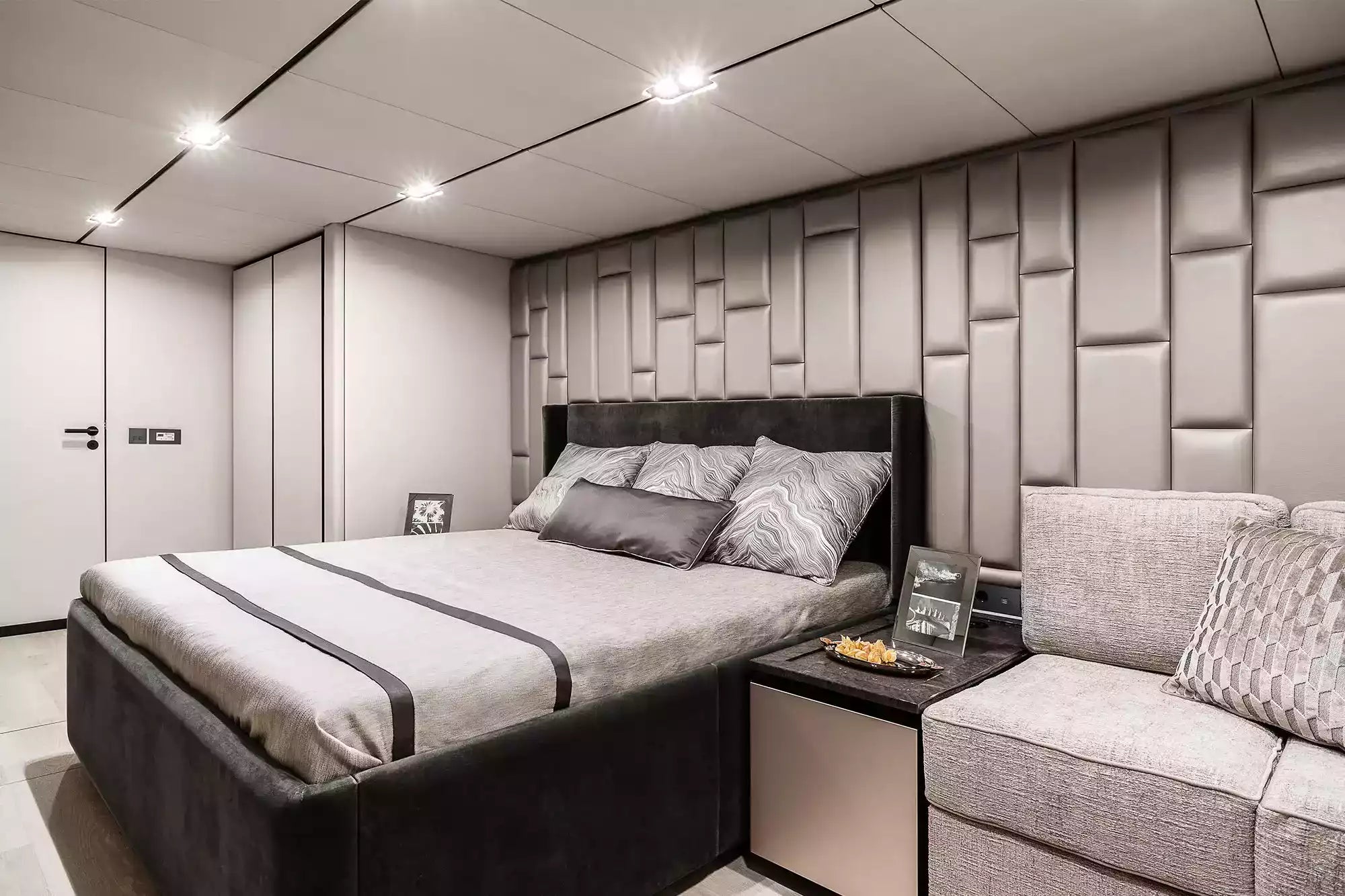 Modern bedroom with a bed, sofa, and decorative wall panels.