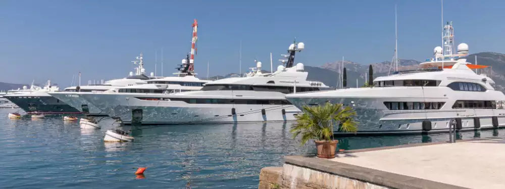 Luxury yachts docked at a marina with clear blue sky and water.