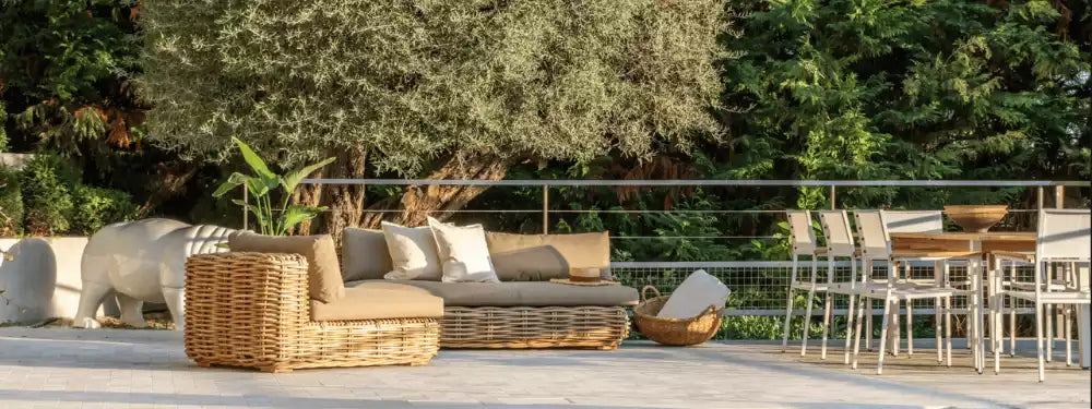 Outdoor patio with wicker furniture, chairs, and a dining table under trees.