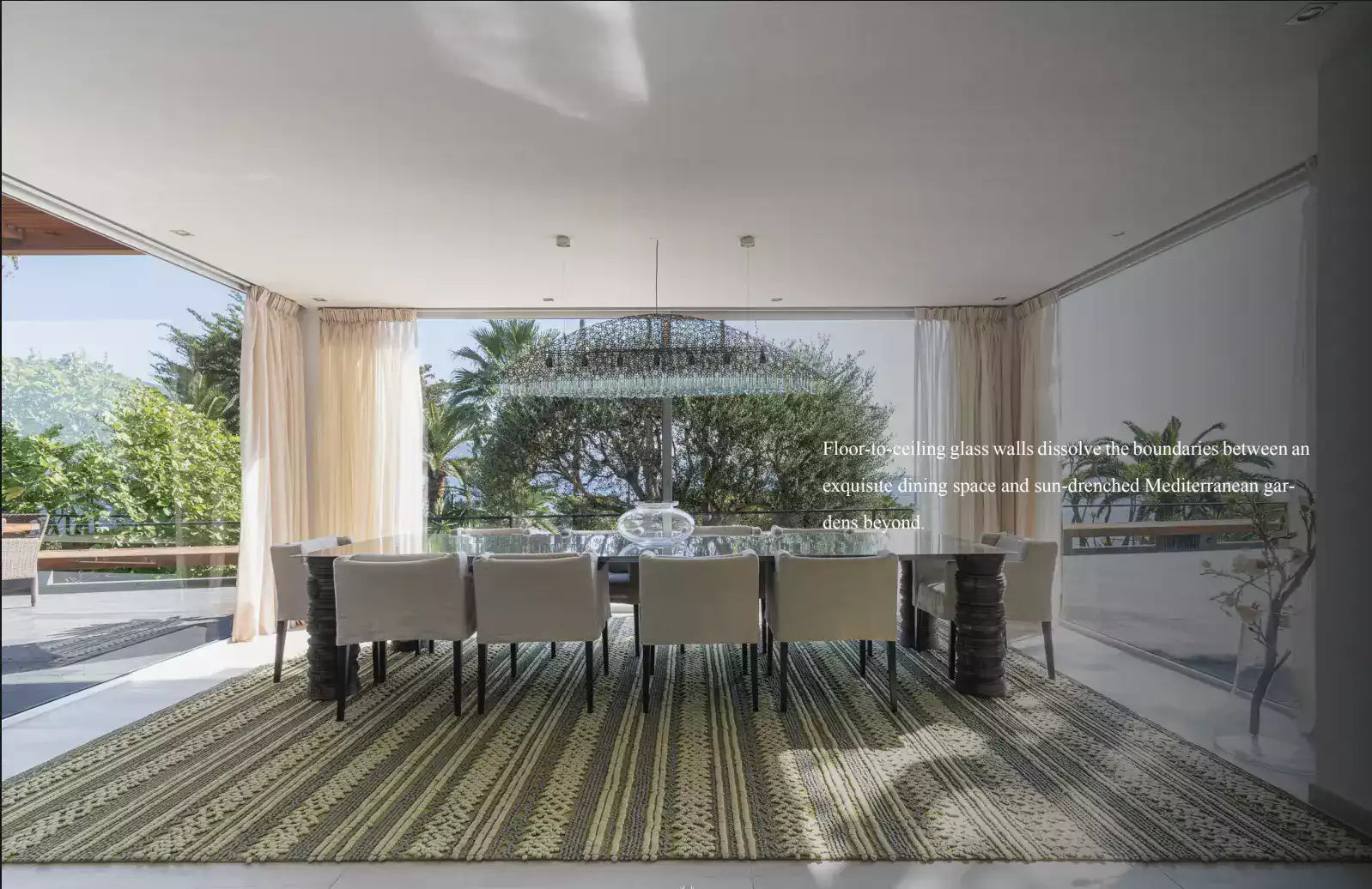 Modern dining area with a large table and chairs, featuring a view of trees and a clear sky.