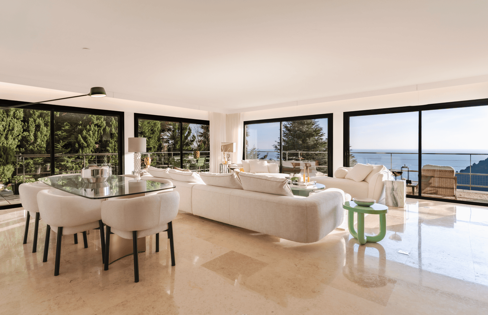 Modern living room with white furniture and large windows overlooking a scenic view.