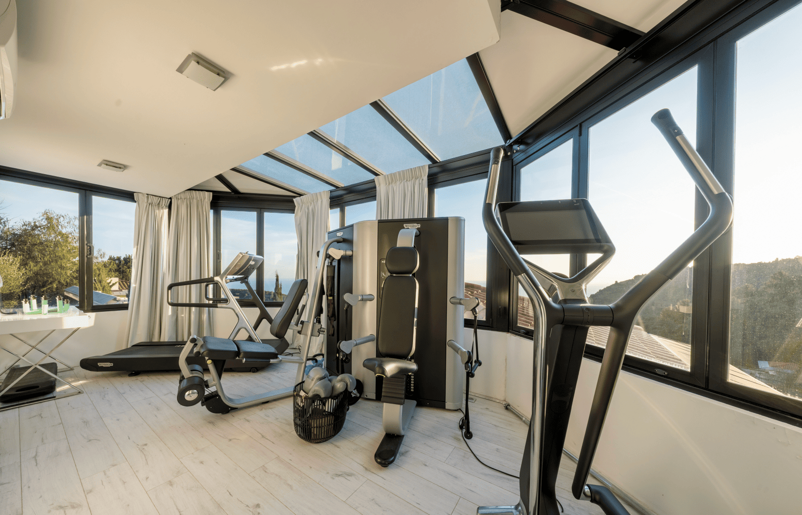 Modern gym interior with exercise equipment and large windows.