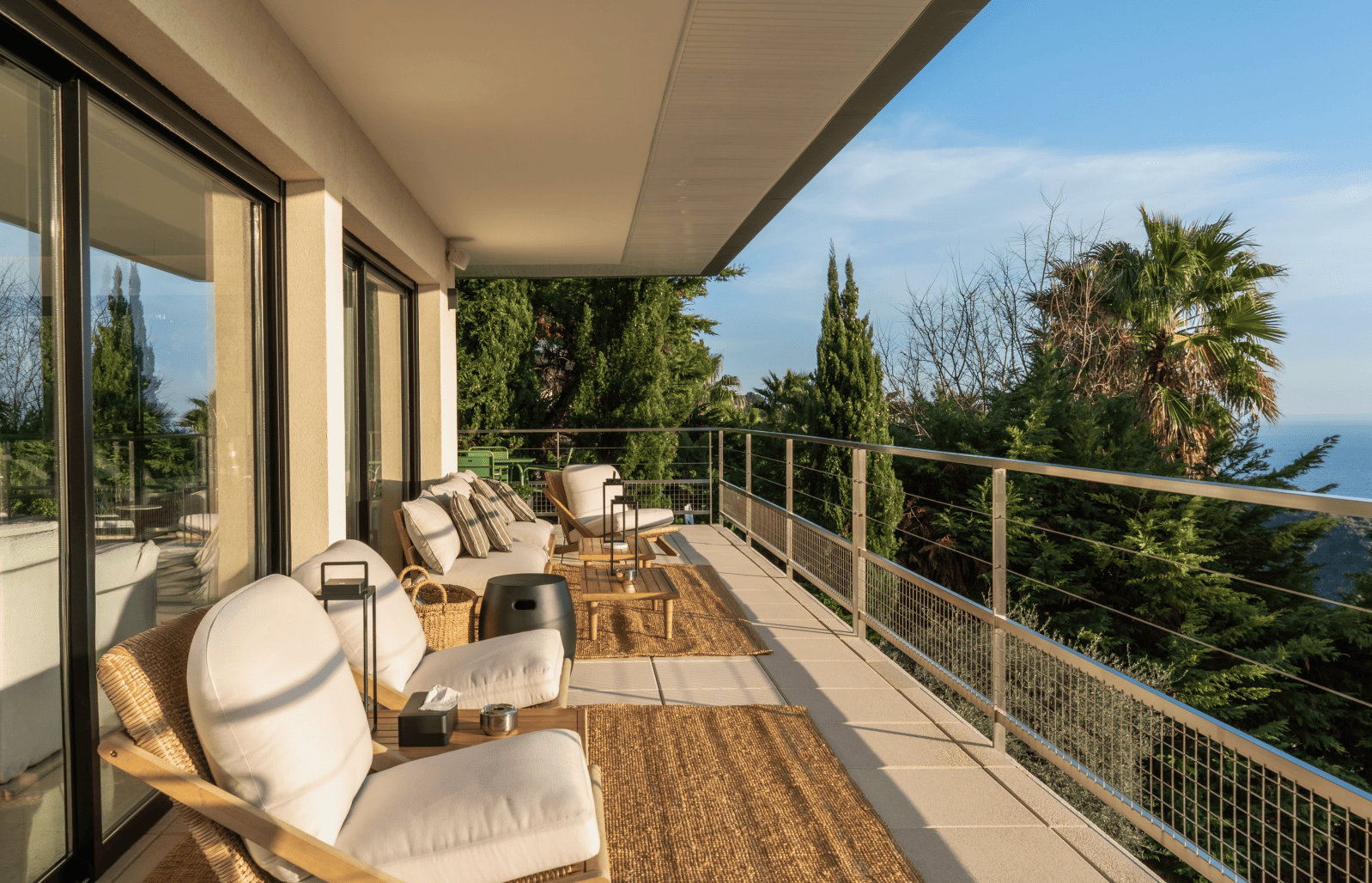 Modern patio with outdoor furniture and a scenic view of trees and sky.