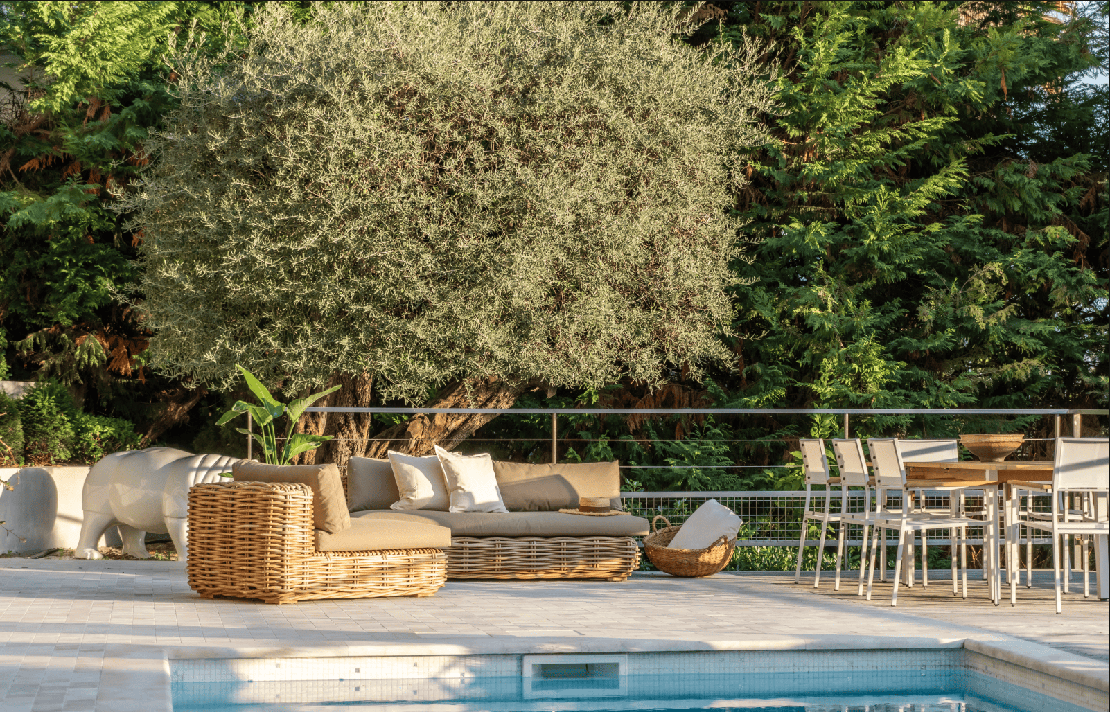 Outdoor patio area with wicker furniture, chairs, and a dining table by a pool.