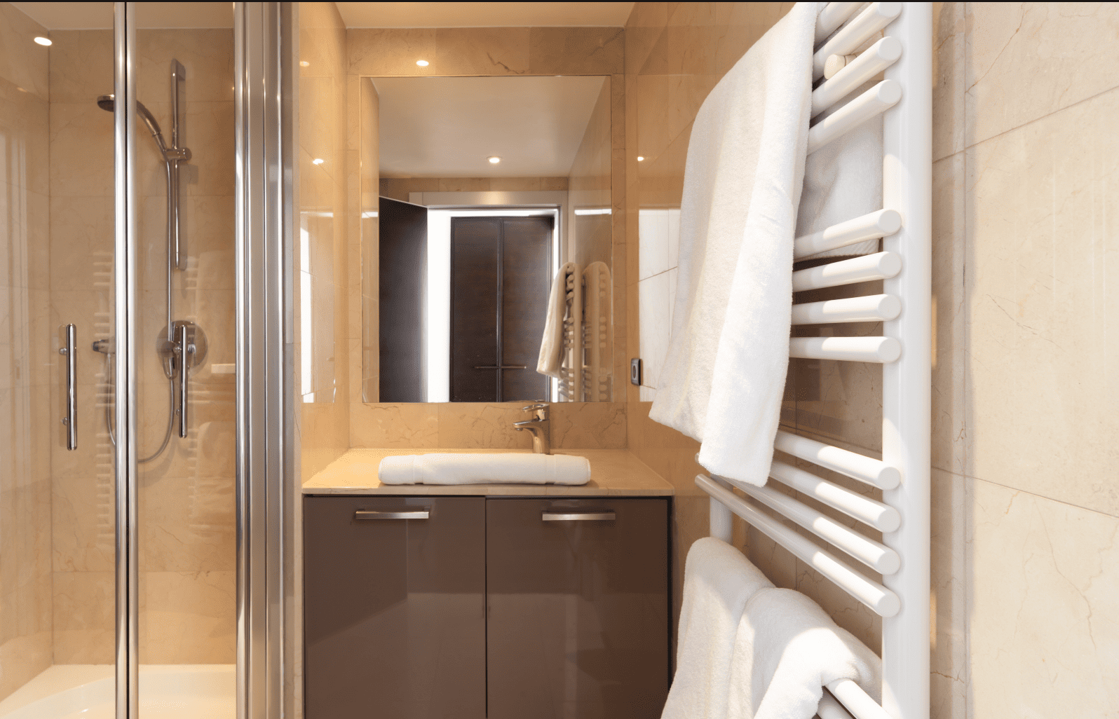 Modern bathroom with shower, sink, and towel rack.