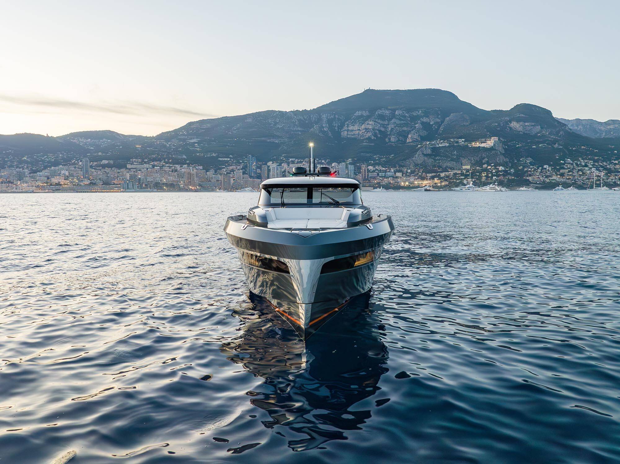 Yacht on a body of water with mountains and cityscape in the background