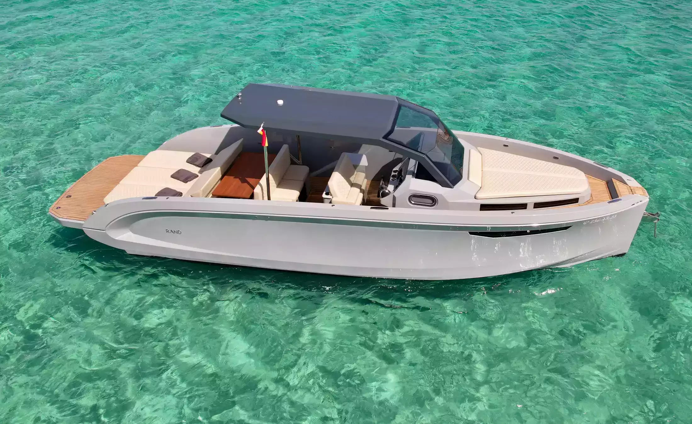 White boat with a black canopy on clear turquoise water