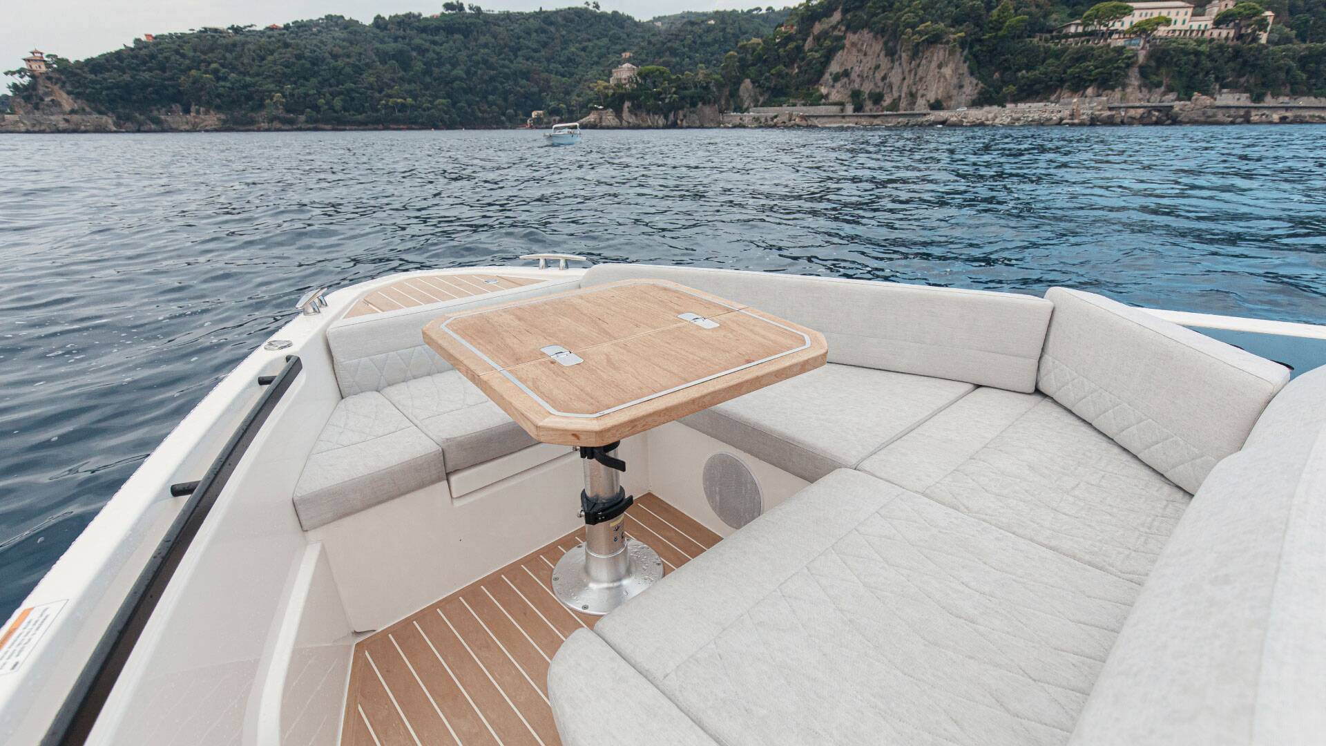 Boat interior with a wooden table on a body of water with a scenic background