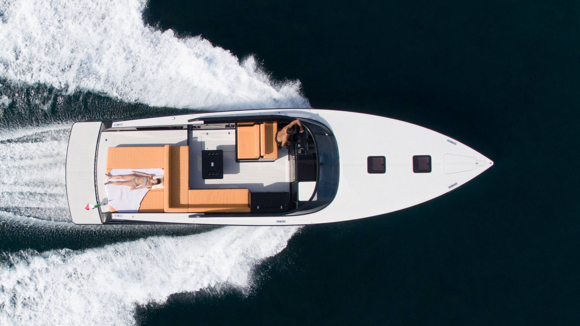 Top-down view of a white speedboat cutting through water