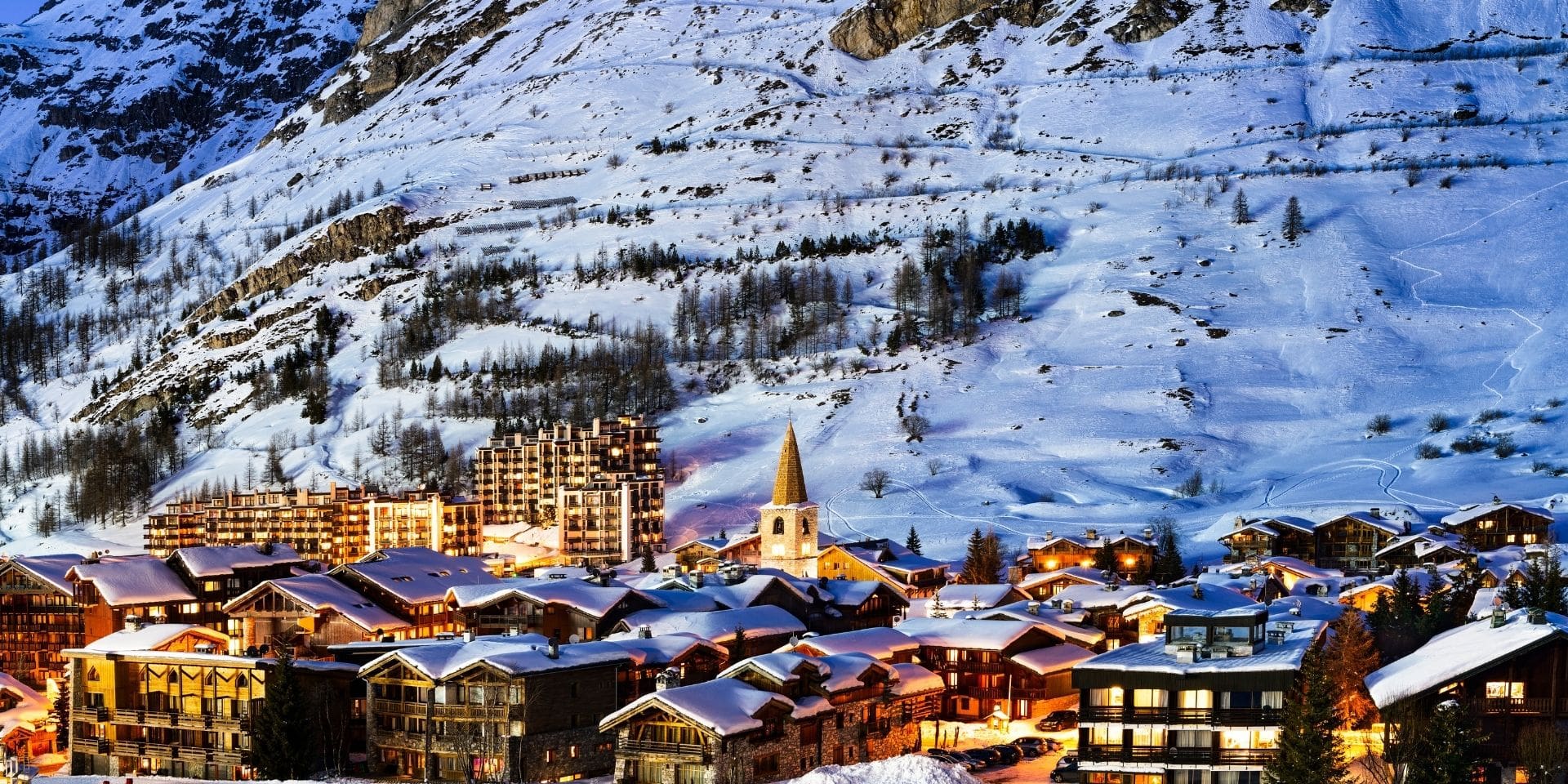 Snow-covered mountain village with illuminated buildings at night
