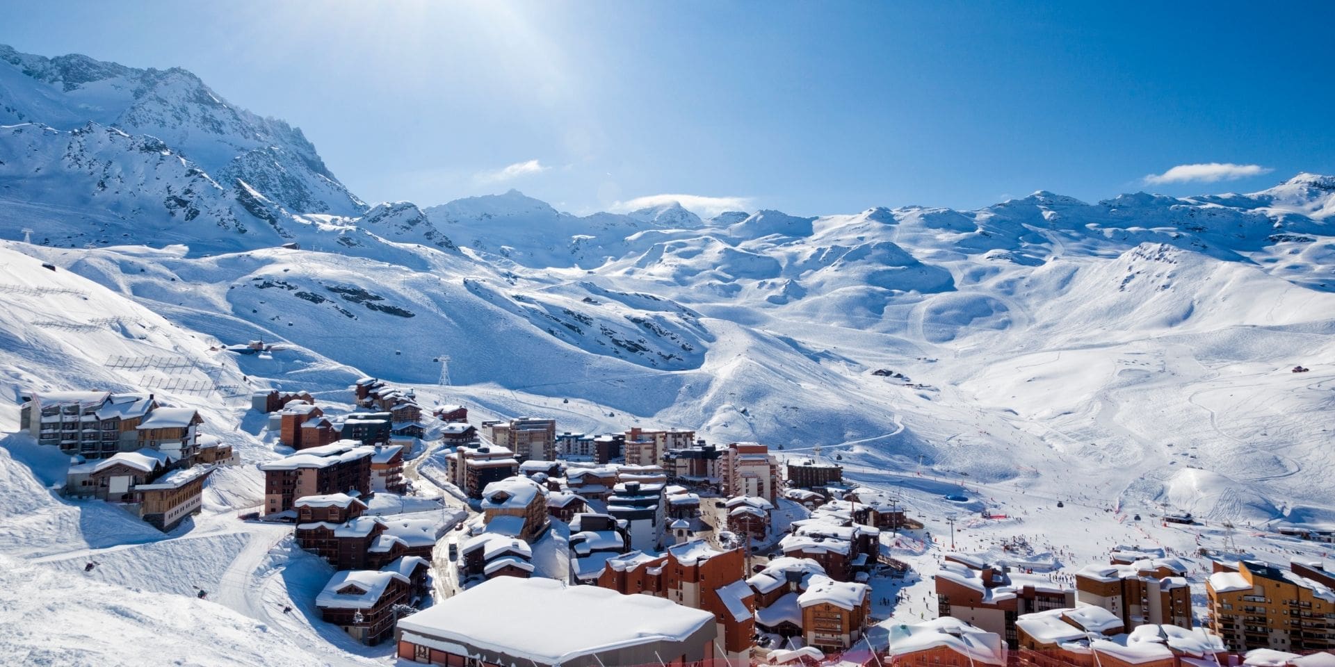 Snow-covered mountain village with ski lifts against a blue sky